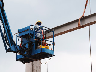 construction worker at construction site using lifting boom machinery