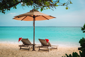 Christmas on beach -chair lounges with Santa hats at sea