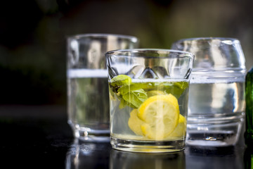 Mojito drink in a transparent glass on wooden surface with white rum,soda,lemon juice,fresh mint leaves,ice cubes and sugar,Close up shot or top shot.