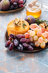 Cheese plate served with grapes, jam, figs, honey and nuts on a rustic background. Copy space.