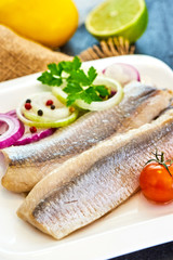 Fototapeta na wymiar Atlantic Marinated herring fillet with pepper, tomatoes, herbs and onion on white plate