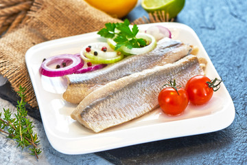 Atlantic Marinated herring fillet with pepper, tomatoes, herbs and onion on white plate