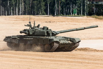 Military or army tank ready to attack and moving over a deserted battle field terrain.