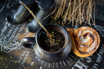 Magical Halloween coffee with gold stars and pumpkin cinnamon roll with witch shoes and broom