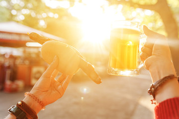 cold glass mug of beer with foam with bratwurst hotdog with sun beams