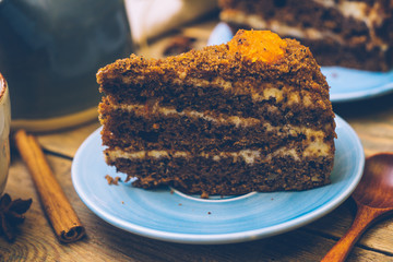 Carrot cake (homemade desserts) whith cinnamon sticks and decorated with spices and cup of tea on wooden background.