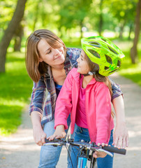 Naklejka premium mother and daughter learning to ride a bicycle