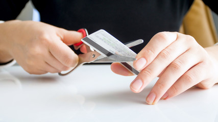 Closeup image of bank female worker cutting expired credti card with scissors