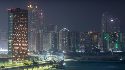 Fototapeta premium Buildings on Al Reem island in Abu Dhabi night timelapse from above.