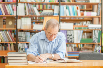 Senior man reading books in a library