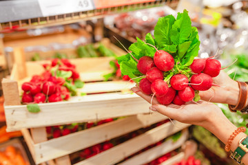 Woman shopping for fresh radish in supermarket, healthy organic vegetables concept