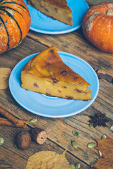 Homemade sliced pumpkin tart pie recipe whith cinnamon, nuts and fresh pumpkin on vintage table wooden table background. Halloween party traditional dessert. Rustic style.