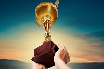Gold cup in hands isolated on white