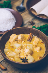Massaman curry (chicken curry) whith cinnamon sticks and plane riсe on wooden background. Coconut milk curry.
