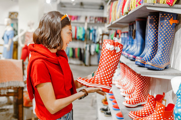 Woman choosing rubber boots at fashion store