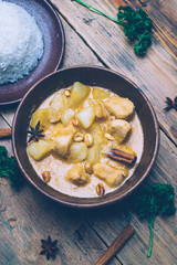 Massaman curry (chicken curry) whith cinnamon sticks and plane riсe on wooden background. Coconut milk curry.