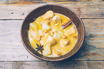Massaman curry (chicken curry) whith cinnamon sticks and plane riсe on wooden background. Coconut milk curry.