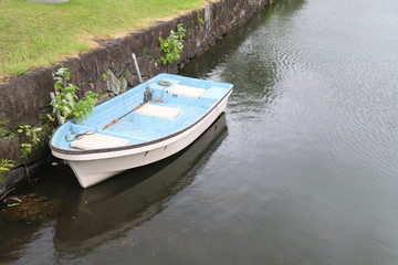 Closeup of old boat lie at the bank of canal with natural background during raining.