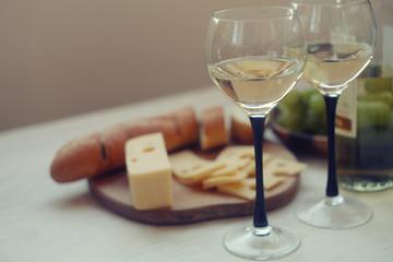 white wine,green gpapes in the plate,slaced cheese and baguette on the cutting board/ 