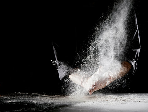 Cloud of flour spraying into air as man rubs hands