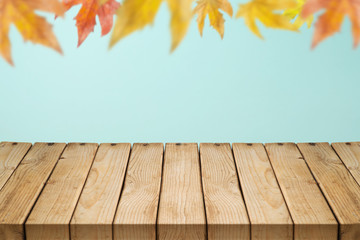 Naklejka na ściany i meble Empty wooden table over autumn leaves blurred background