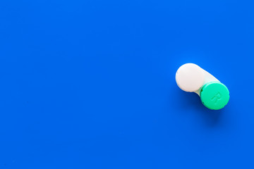 Improve vision concept. Contact lenses in container on blue background top view copy space