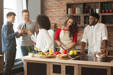 Group of multiracial friends cheering while cooking at kitchen