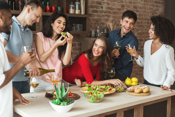 Group of friends drinking and eating in loft kitchen