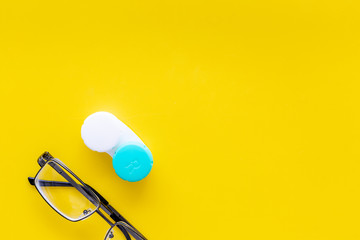 Products help see better. Glasses with transparent optical lenses and eye lenses on yellow background top view space for text closeup