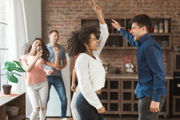 Young happy diverse couple dancing at home party
