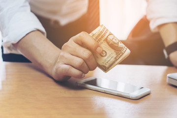 Handsome young businessman holding money, finance, technology and e-commerce concept - close up of smartphone with black blank screen and dollar money.selective focus