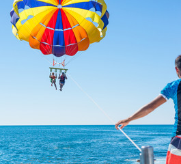 Happy couple Parasailing in Dominicana beach in summer. Couple under parachute hanging mid air. Having fun. Tropical Paradise. Positive human emotions, feelings, family, children, travel, vacation.