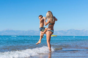 Young mother and smiling baby boy son playing on the beach in the day time