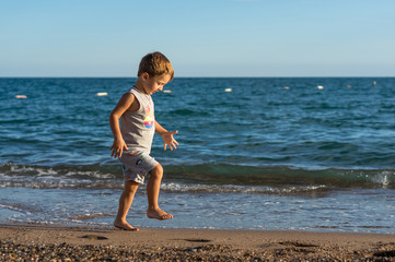 Fototapeta na wymiar Smiling little baby boy playing in the sea. Positive human emotions, feelings, joy.