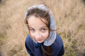 closeup of pretty little caucasian girl in hood and jacket with hair wind blowing