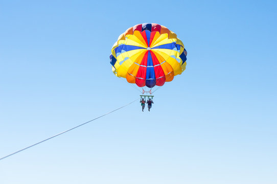 Happy couple Parasailing in Dominicana beach in summer. Couple under parachute hanging mid air. Having fun. Tropical Paradise. Positive human emotions, feelings, family, children, travel, vacation. 