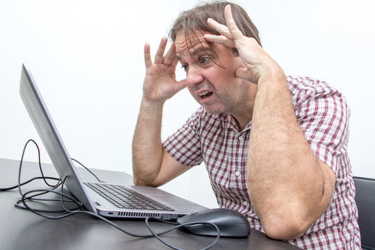 The Confused Unhappy User Is Looking At The Computer Screen. Surprised Stressed Man Looking At Laptop. System Error On Computer.