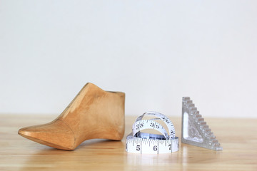 Wooden last shoe with measuring tape on white background