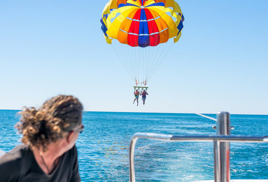 Happy couple Parasailing in Dominicana beach in summer. Couple under parachute hanging mid air. Having fun. Tropical Paradise. Positive human emotions, feelings, joy. Family spring holidays.