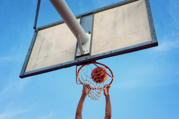 Street basketball athlete performing slam dunk on the court © herraez