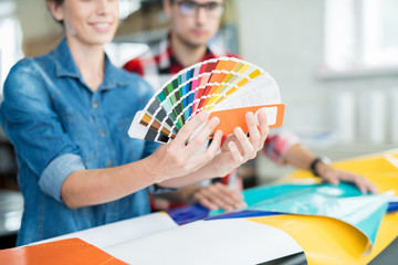 Crop view of young communicating man and woman exploring palette of colors and choosing shades