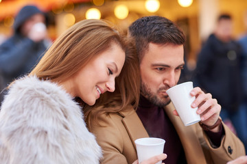 Portrait of a beautiful young couple drinking mulled wine in a christmas market.