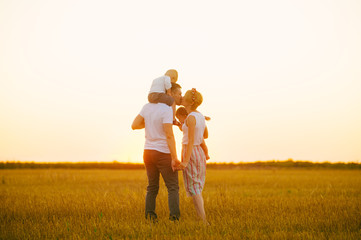 Young family at sunset kissing, family mother father and boys