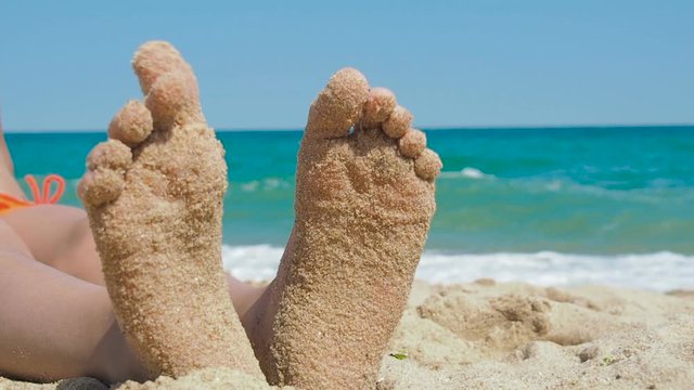 Feet of a child on the beach. Feet in the sand against the background of the sea.