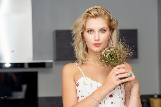 portrait of beautiful young blonde woman with bouquet of flowers
