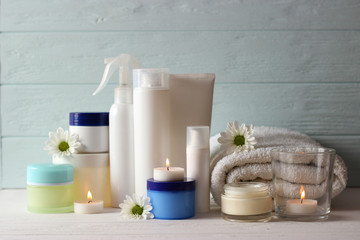 a set of usurious cosmetics, a towel and a candle on a wooden background. Skin care.
