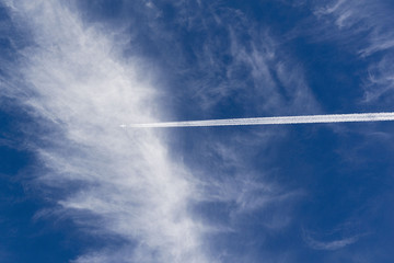White trace of a flying plane in the blue sky
