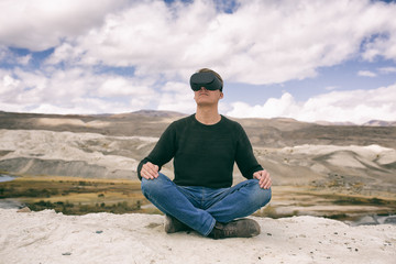 Naklejka na ściany i meble man in glasses of virtual reality meditates against the background of nature. The man in the game.