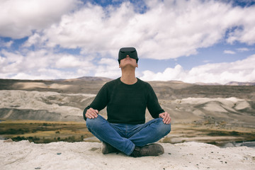 Naklejka na ściany i meble man in glasses of virtual reality meditates against the background of nature. The man in the game.