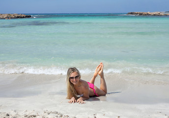 Fototapeta na wymiar Smiling beautiful blond girl are lying on the beach in sunglasses